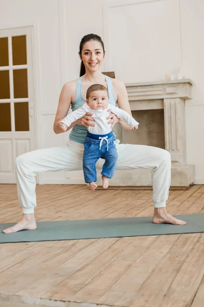 Madre con bebé niño practicando yoga - foto de stock