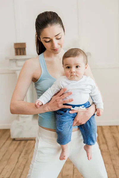 Femme portant bébé enfant sur les bras — Photo de stock