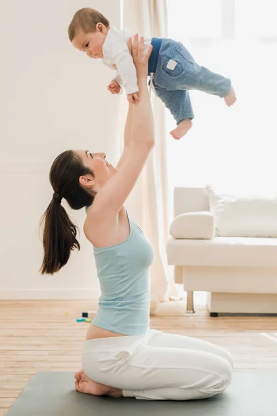 Joven madre jugando con su hijo - foto de stock