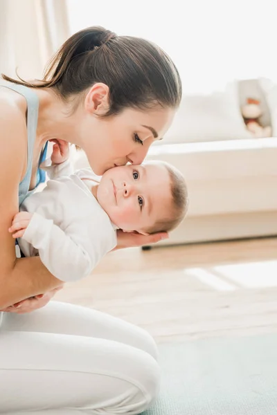 Joven madre abrazando bebé niño - foto de stock