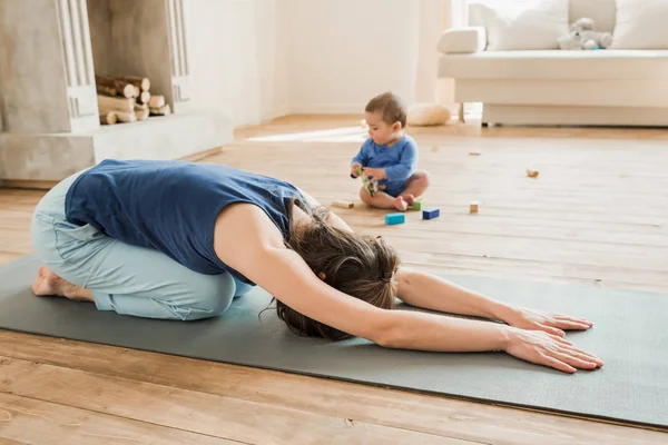 Madre con bebé niño practicando yoga - foto de stock