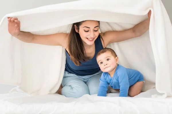 Mother with her son playing under blanket — Stock Photo