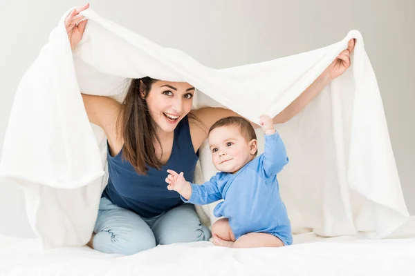 Madre con su hijo jugando debajo de la manta - foto de stock