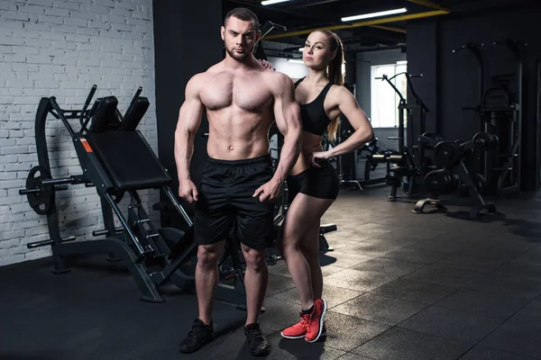 Sportliches Paar posiert im Fitnessstudio — Stockfoto