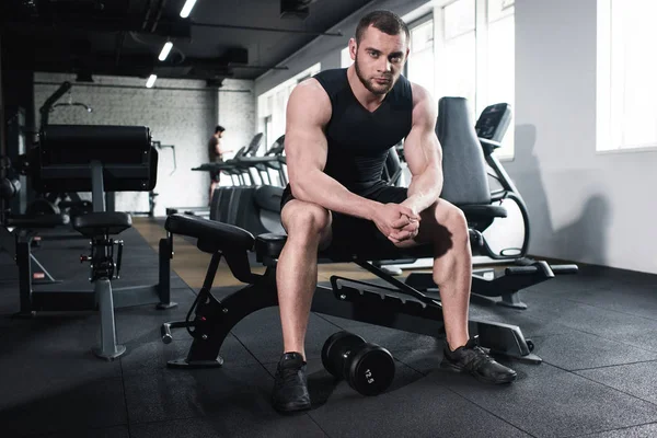 Sportler sitzt im Fitnessstudio und blickt in die Kamera — Stockfoto