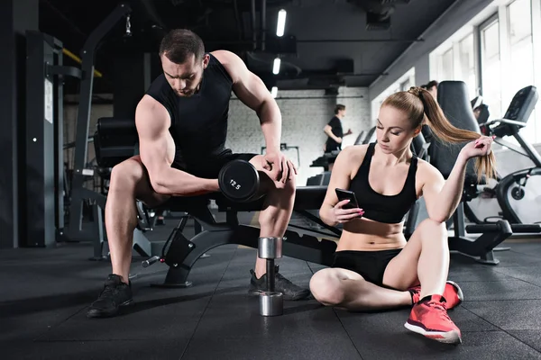 Man training while woman using smartphone — Stock Photo