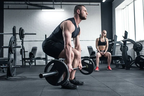 Man doing strength training while woman sitting — Stock Photo