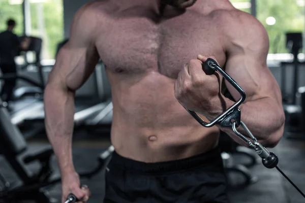 Entrenamiento del culturista con la máquina del peso en el gimnasio - foto de stock