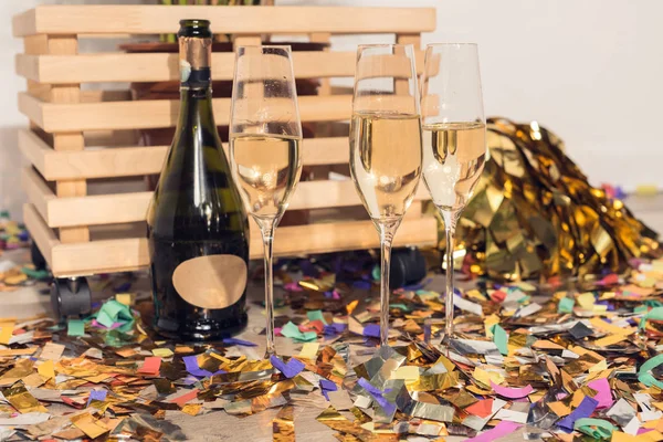 Champagne with confetti and wooden box — Stock Photo