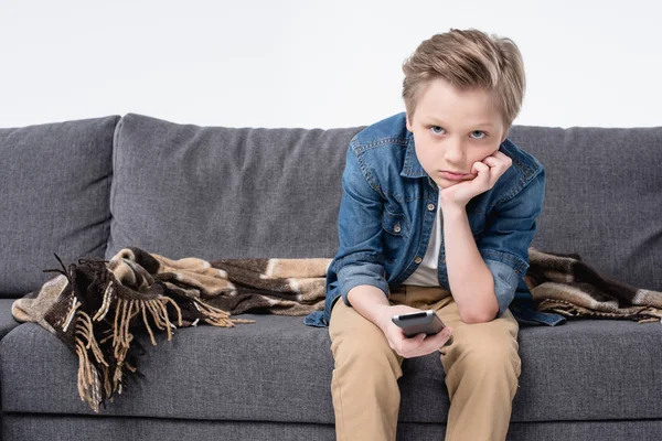 Bored kid boy sitting on sofa — Stock Photo