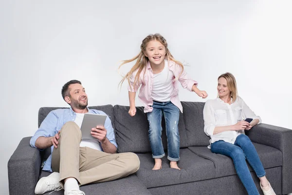 Padre y madre sentado mientras hija saltando - foto de stock