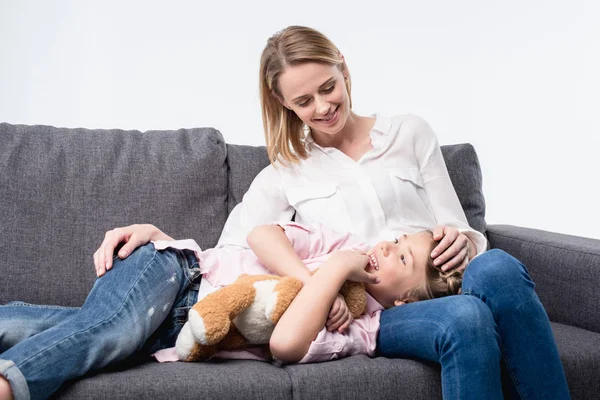 1 madre con hija pequeña sentada en el sofá - foto de stock