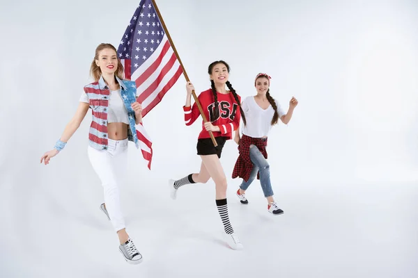 Mujeres multiétnicas caminando con bandera americana - foto de stock