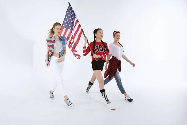 Muchachas multiétnicas caminando con bandera americana - foto de stock