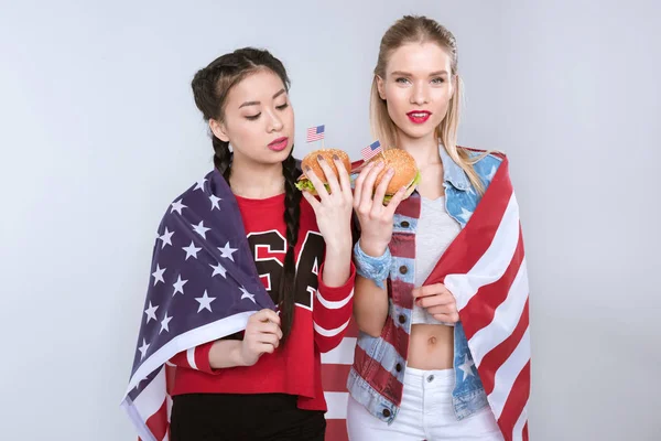 Chicas con bandera de EE.UU. comiendo hamburguesas - foto de stock
