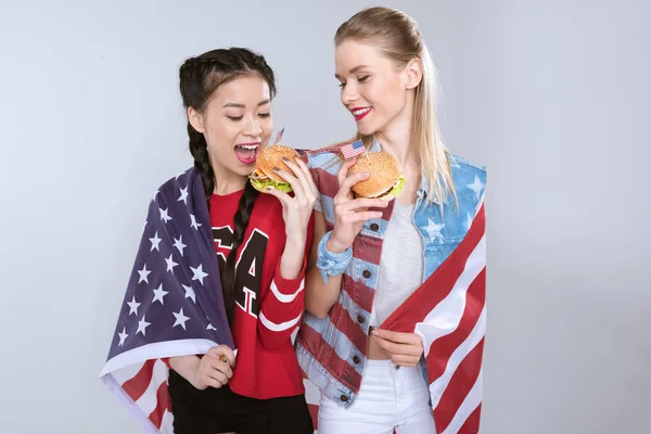 Mulheres com bandeira dos EUA comer hambúrgueres — Fotografia de Stock