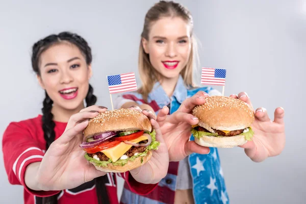 Mujeres multiétnicas felices sosteniendo hamburguesas - foto de stock