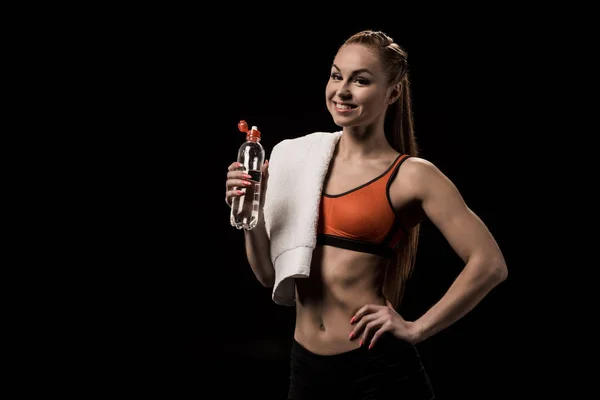 Athlete with towel holding bottle of water — Stock Photo