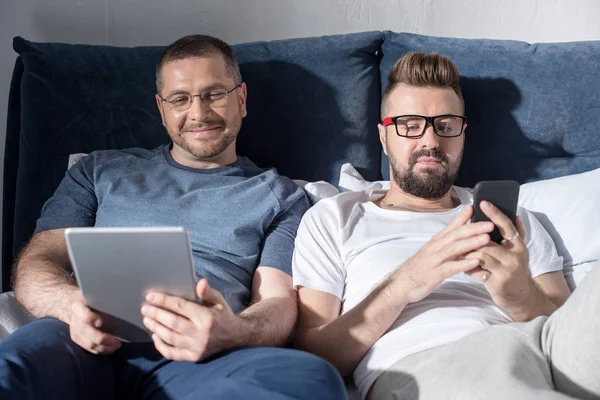 Pareja homosexual usando dispositivos digitales - foto de stock