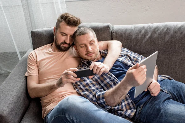 Couple homosexuel utilisant des appareils numériques — Photo de stock