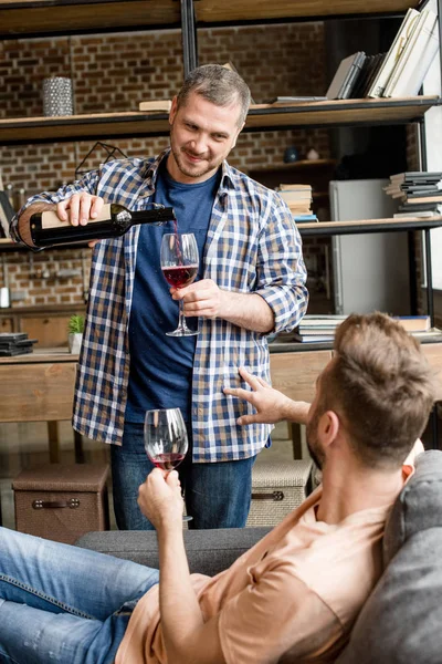 Homem derramando vinho durante conversa com namorado — Fotografia de Stock