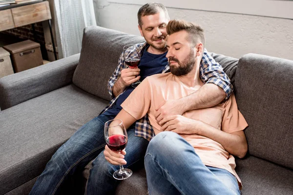 Pareja homosexual bebiendo vino en casa - foto de stock