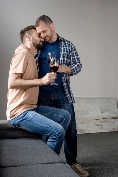 Pareja homosexual abrazando y bebiendo vino - foto de stock