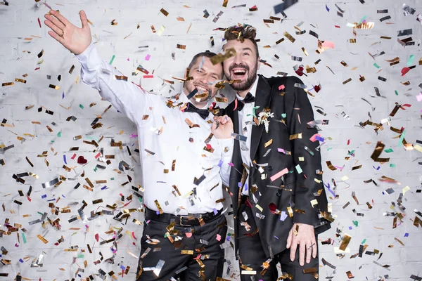 Happy homosexual couple celebrating with confetti — Stock Photo