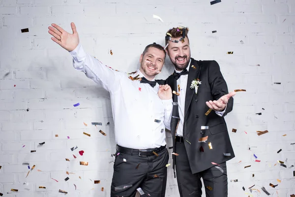Feliz pareja homosexual celebrando con confeti - foto de stock