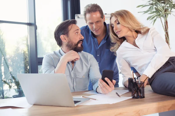 Compañeros de trabajo de mediana edad mirando teléfono inteligente - foto de stock