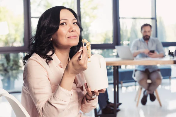 Зріла азіатська бізнес-леді їсть локшину — стокове фото