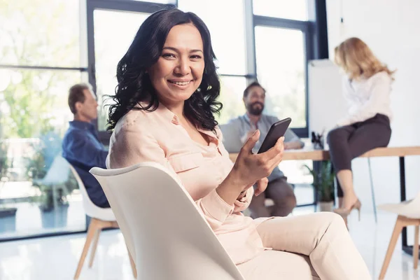 Maduro asiático mujer de negocios usando smartphone - foto de stock