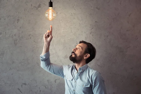 Homme pointant vers une ampoule lumineuse — Photo de stock