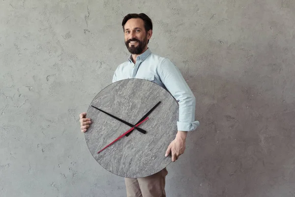 Sonriendo hombre maduro sosteniendo reloj - foto de stock