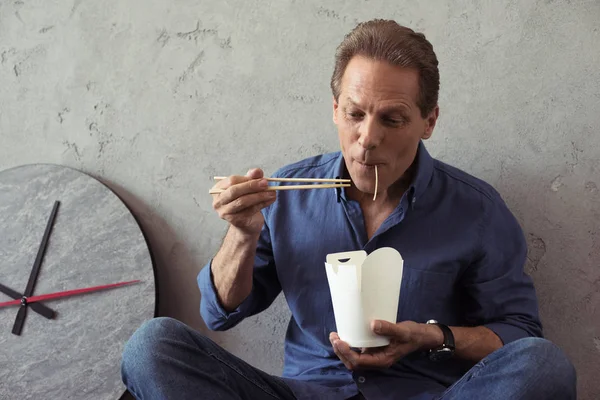 Hombre de mediana edad comiendo fideos - foto de stock