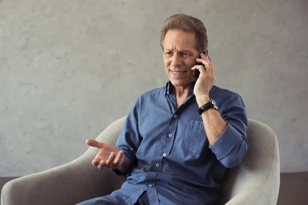 Emotional mature man talking on smartphone — Stock Photo