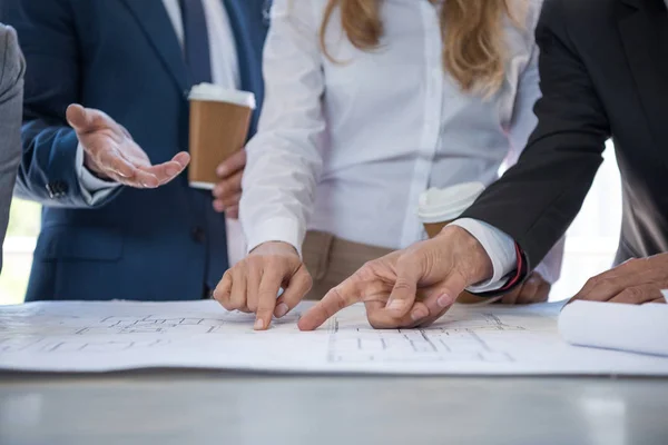 Architects in formal wear pointing at blueprints — Stock Photo