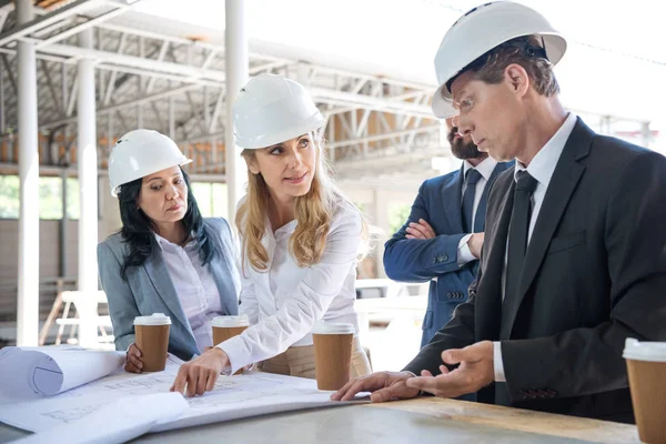 Architetti in abbigliamento formale che lavorano con cianografie — Foto stock