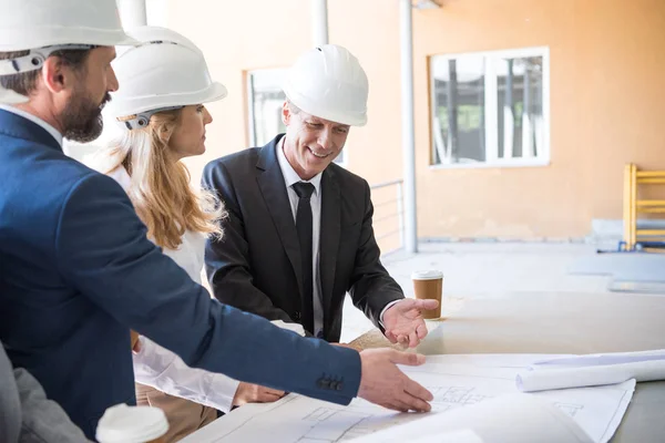 Contractors in formal wear working with blueprints — Stock Photo
