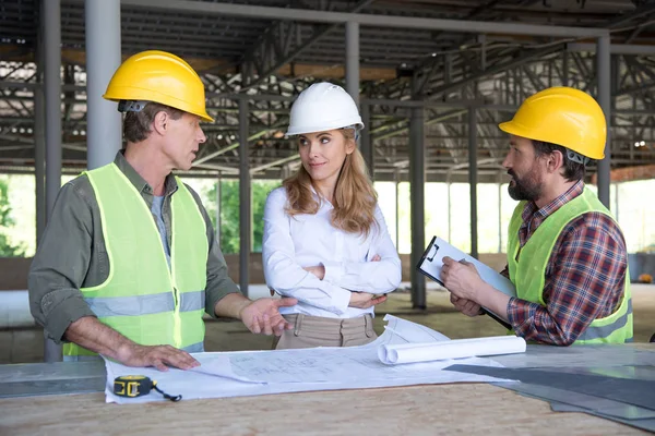 Constructores y contratista hablando en el sitio de construcción - foto de stock