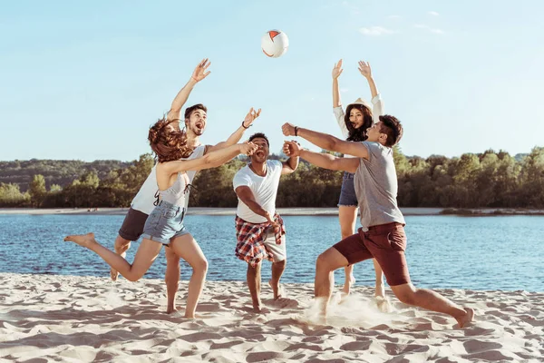 Amigos jugando voleibol de playa a orillas del río - foto de stock