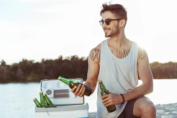 Man holding bottles of beer on riverside — Stock Photo