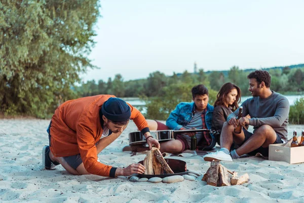 Freunde versuchen, am Strand ein Lagerfeuer zu machen — Stockfoto