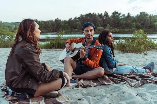 Mann mit Freunden spielt Gitarre am Strand — Stockfoto