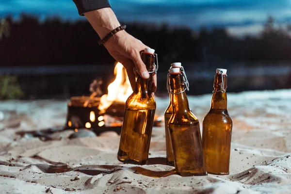 Human hand taking bottle of beer — Stock Photo