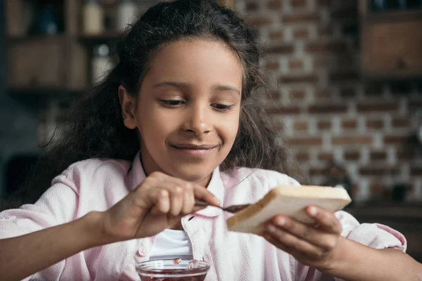 Girl putting jam on toast — Stock Photo