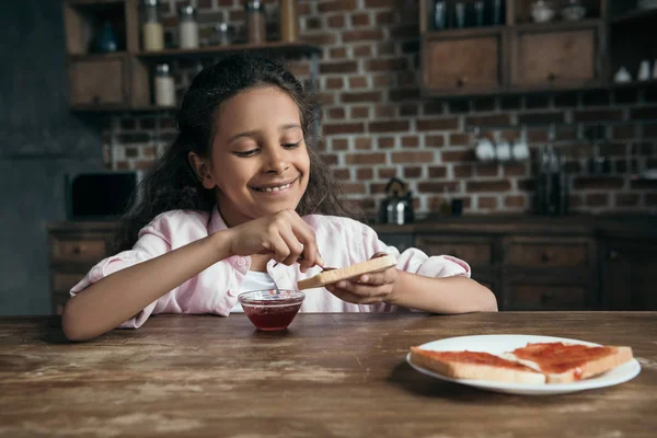 Girl putting jam on toast — Stock Photo