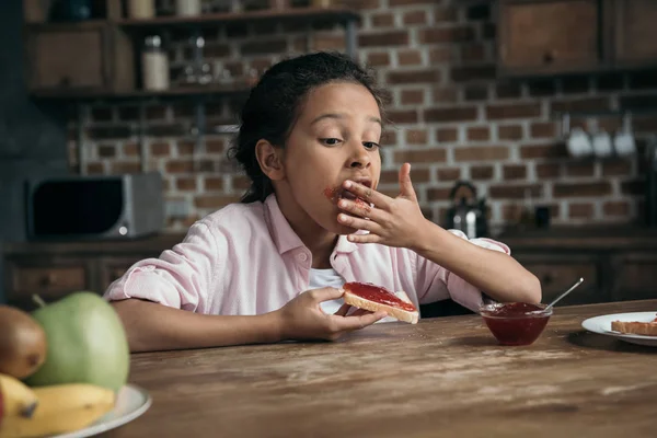 Girl eating toast with jam — Stock Photo