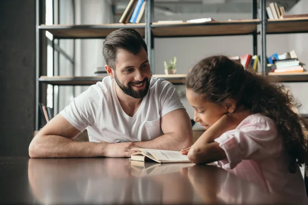 Girl reading book with father — Stock Photo