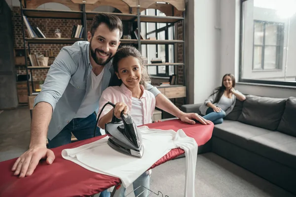 Padre con hija planchando ropa - foto de stock